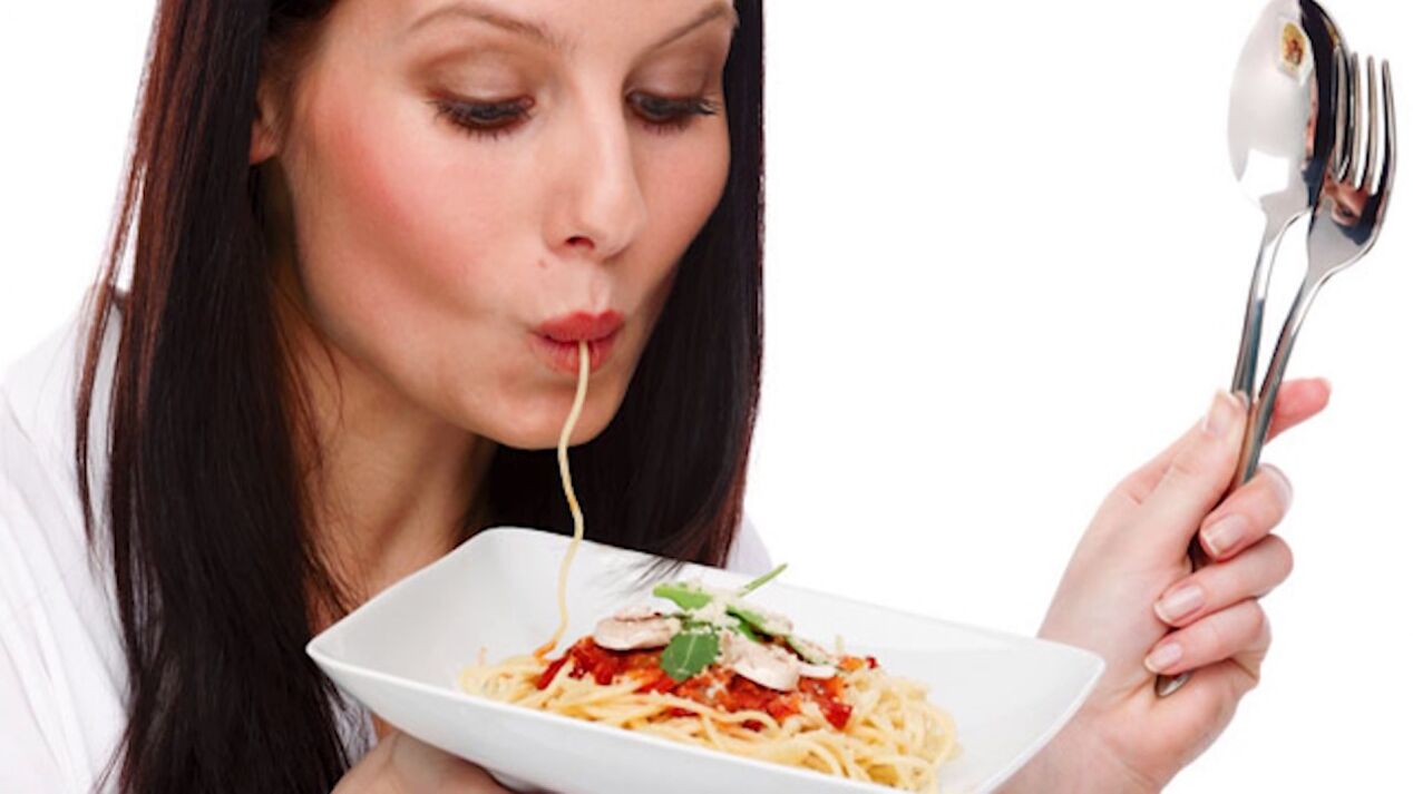 Frau isst Spaghetti, um ihren Bauch zu schlank zu machen